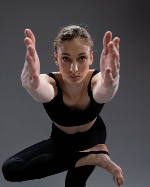 Woman in a graceful yoga pose against a dark background with cyan light accents.